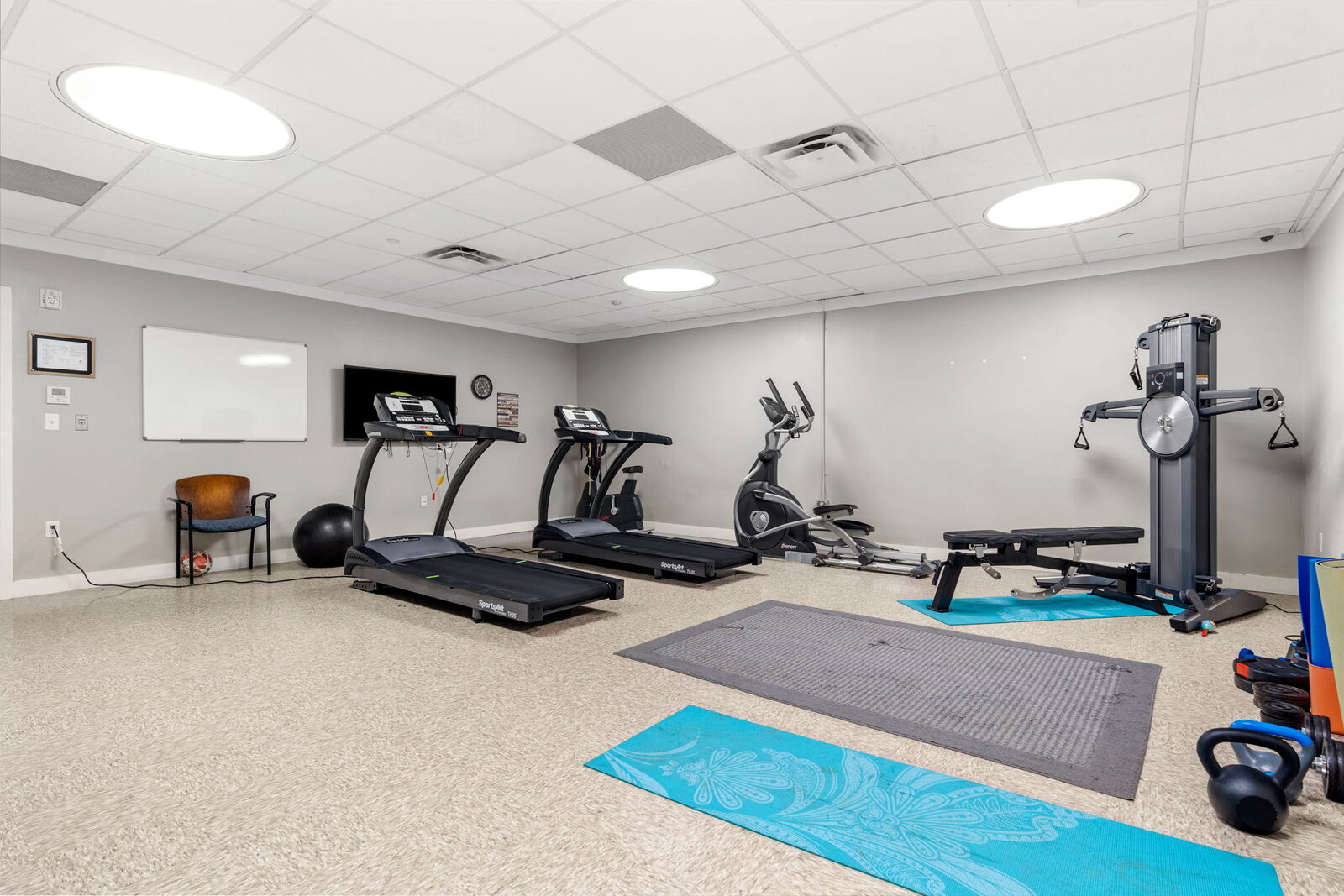 Fitness room with treadmills, an elliptical, weights and yoga mats